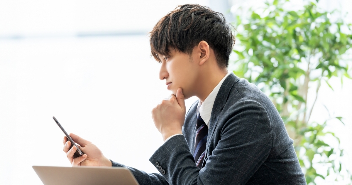 スマホを見つめて考え込む男性
